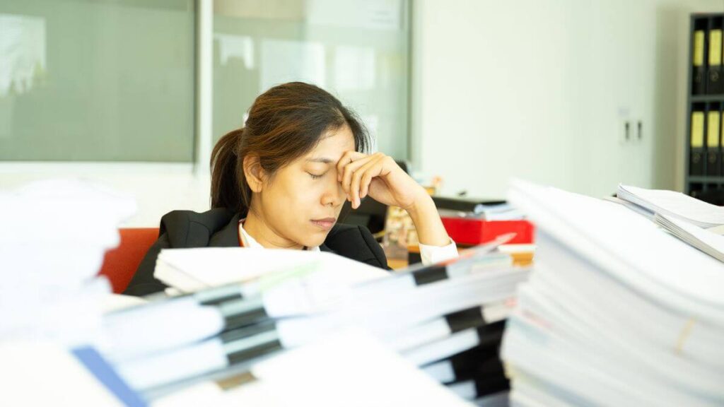 a tired finance manager sitting in front of piles of documents